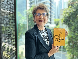 Sylvia Fernandes holding the orange Bye Bye Black Cat book